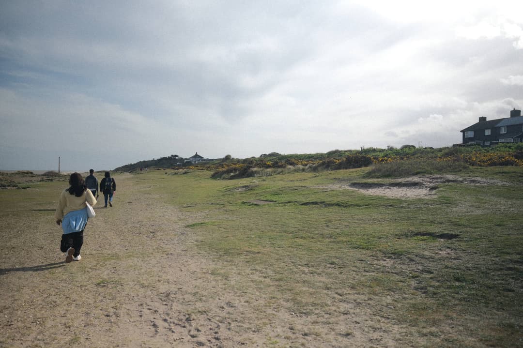 people walking on along a path, with the sea to the left and the sloping shoreline to the right